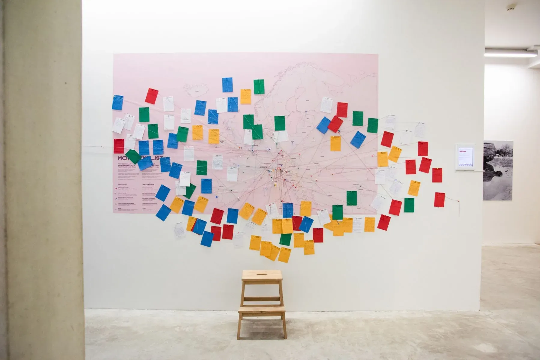 A printed map of Europe on a gallery wall, covered with colour-coded cards