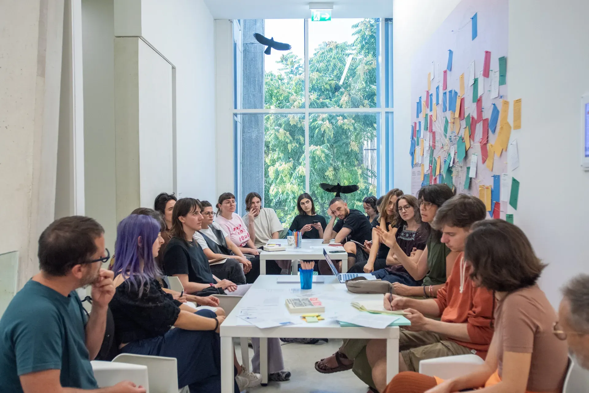 Workshop participants around tables, with the map installation on the wall