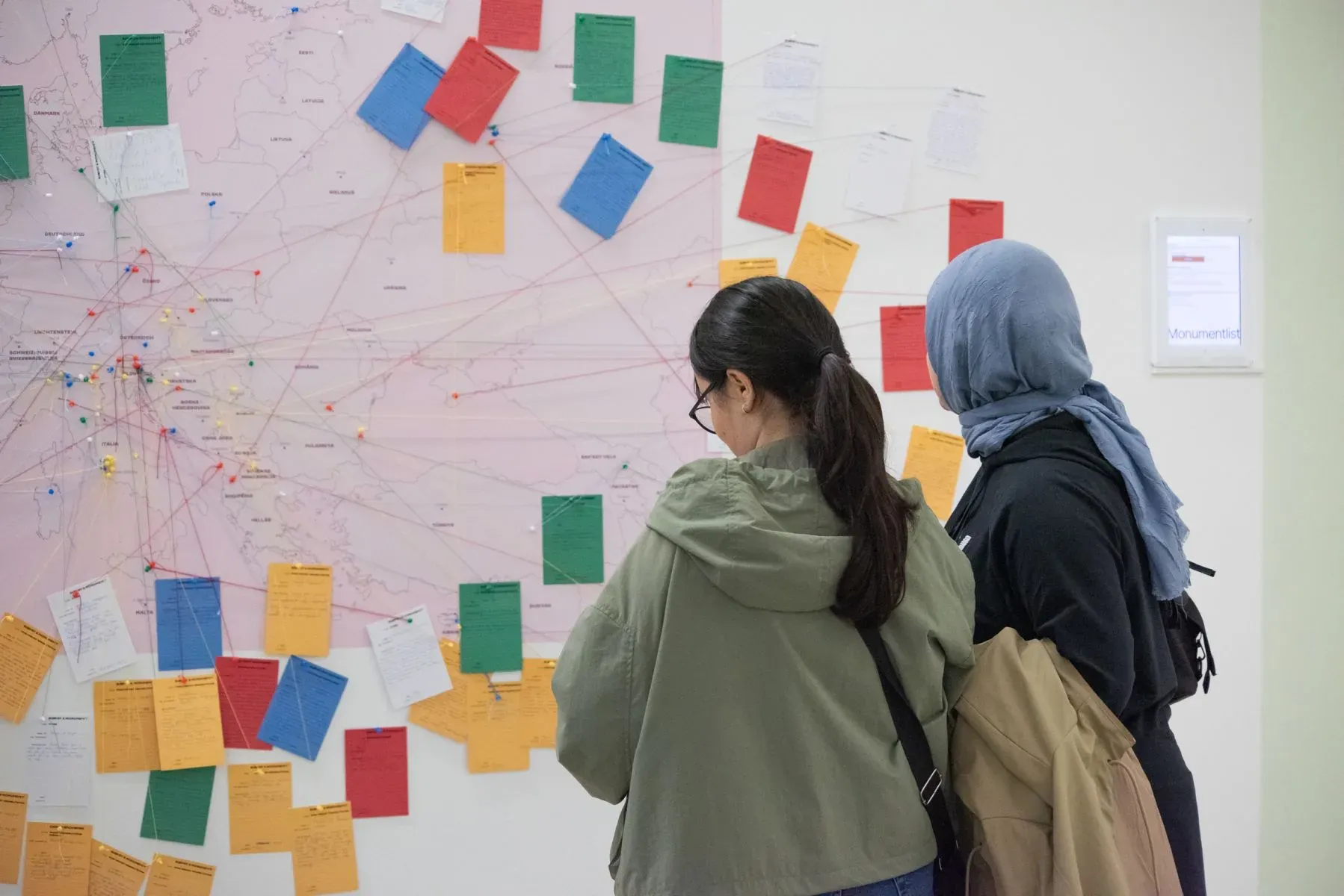 Two visitors reading the cards pinned to the map