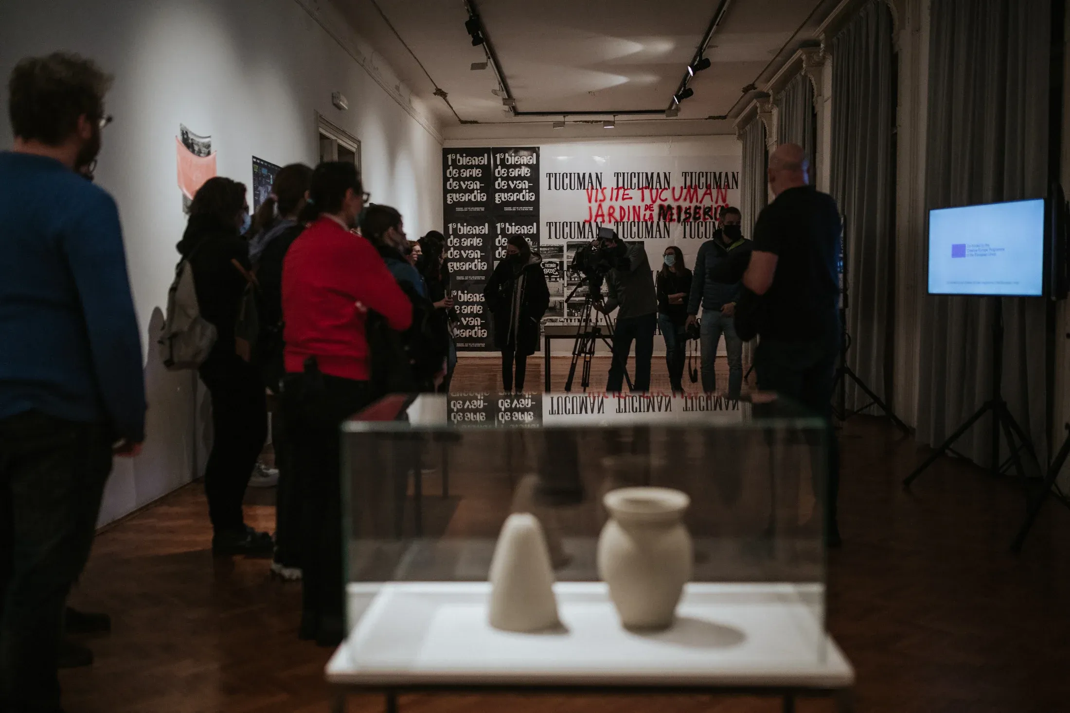 Visitors around the vitrine, with posters on the wall behind